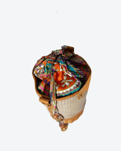 Tory Small Rattan Basket in Brown by Havana & Co. – Hand-woven rattan and raffia bag with leather details and colorful drawstring lining.