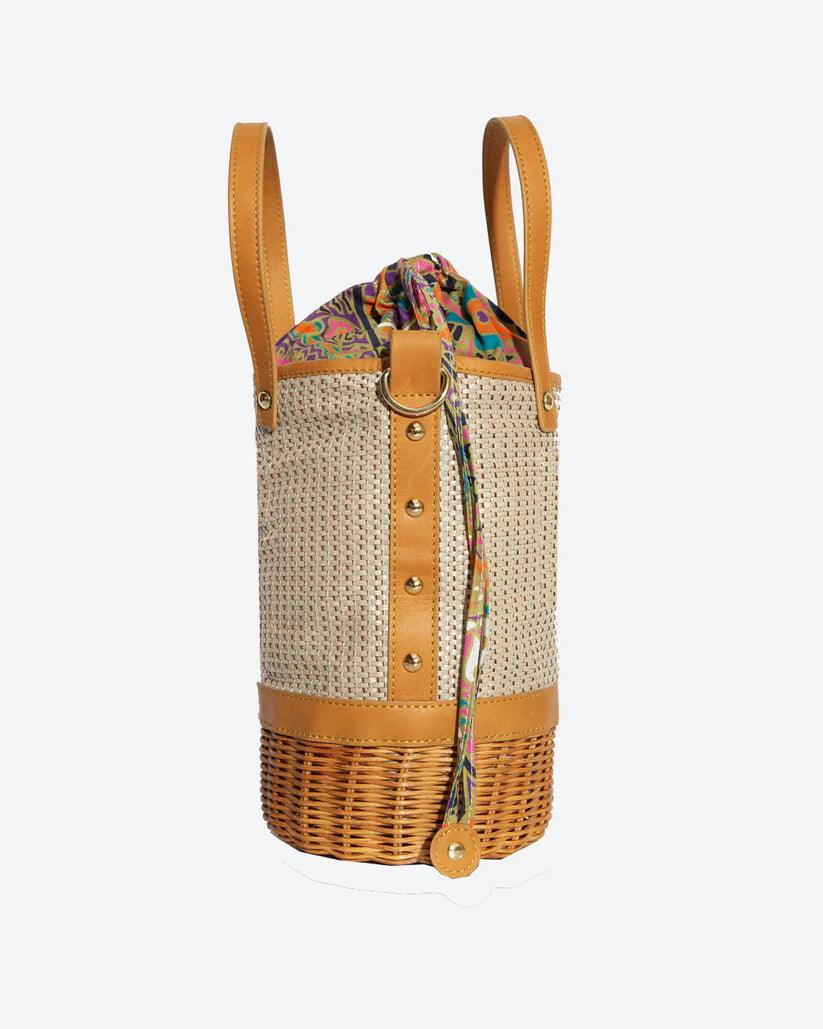 Tory Small Rattan Basket in Brown by Havana & Co. – Hand-woven rattan and raffia bag with leather details and colorful drawstring lining.